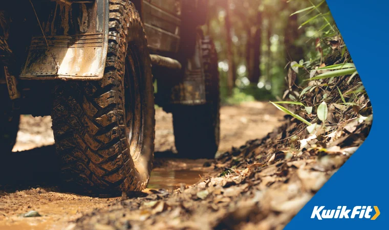 A 4x4 in the dirt with muddy tyres.