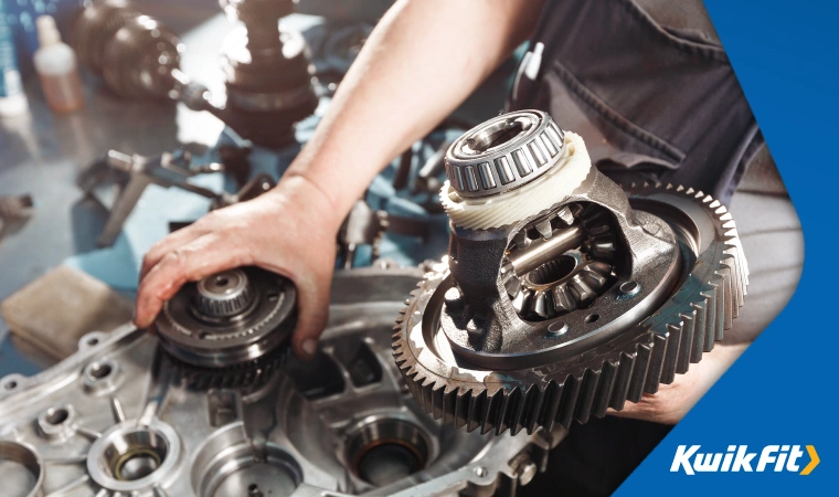 An auto technician with a disassembled car gearbox.