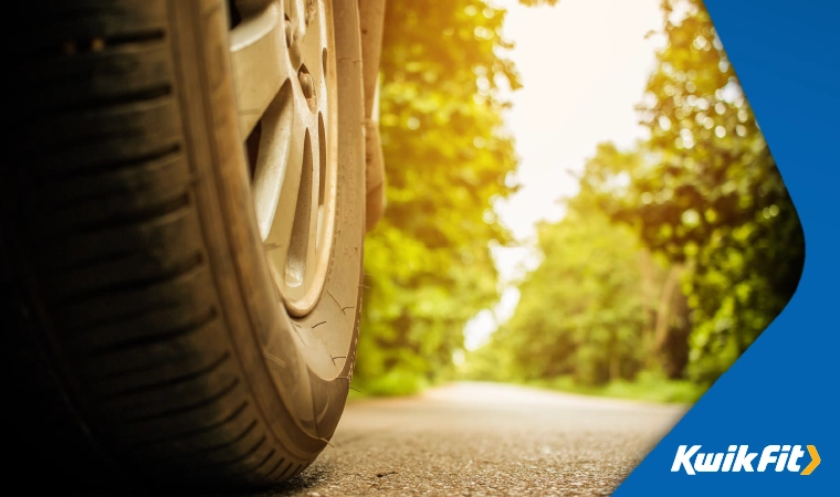 A close-up of a car tyre parked on a sunny road.