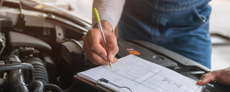 Car technician conducting mot checks under the car bonnet 