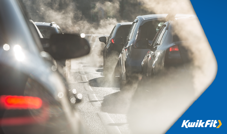 Queue of cars in traffic with smoke rising from each car exhaust.