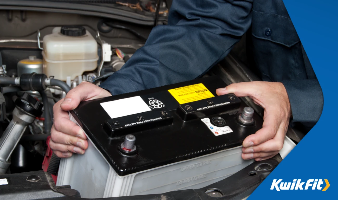 Technician lifting a battery out of a vehicle.