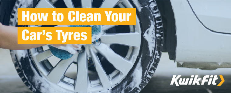 Person cleaning a wheel and tyre covered in soap with a blue sponge.