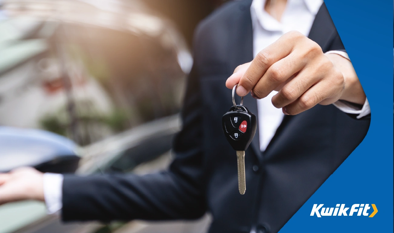 Person in suit handing over the keys of a vehicle.