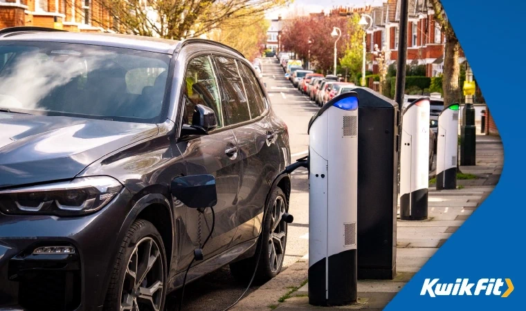 Black hybrid SUV plugged in and charging on a typical Victorian street in the UK.