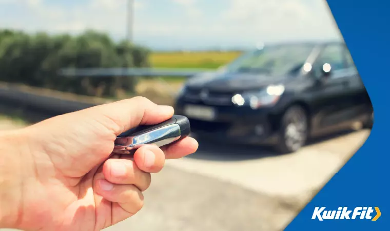 A driver approaches their keyless entry car, pressing the unlock button.