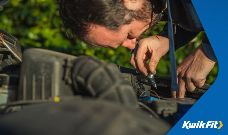 A vehicle with it's bonnet up as a man replaces a headlight