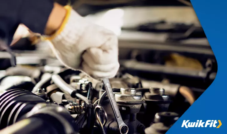 Mechanic using a spanner to perform routine maintenance in a car's engine bay.