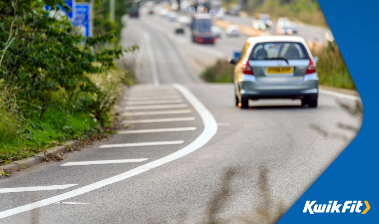 Silver car driving on slip road to join on to the motorway.