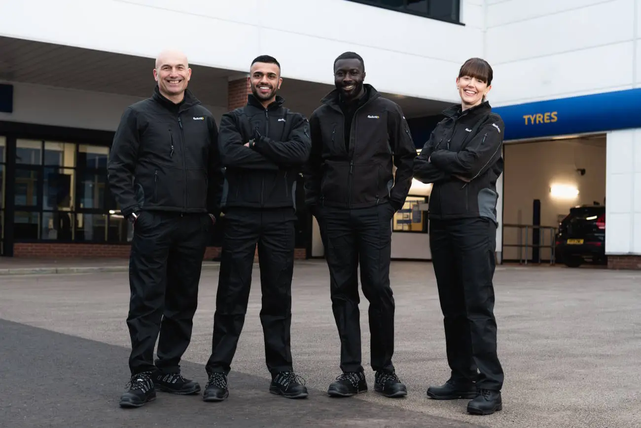 Kwik Fit technicians posing outside Kwik Fit centre.