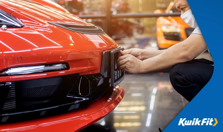 A person prepares a car's number plate bracket for a private number plate.