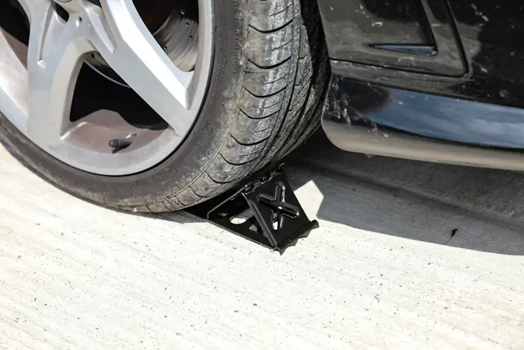 Person putting wheel chocks underneath car wheels