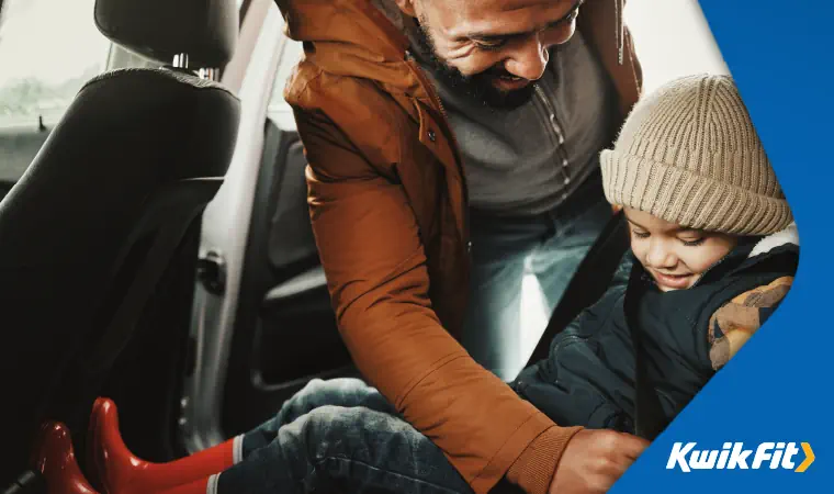 A father putting his child's seatbelt on.