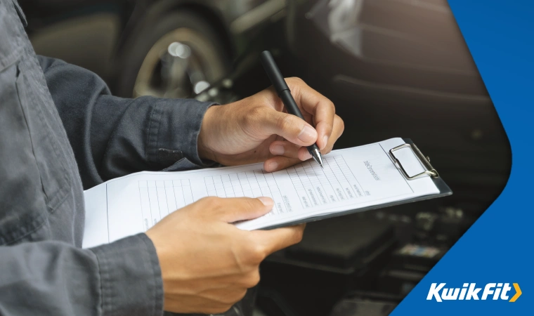 Mechanic filling out a service form for a car.