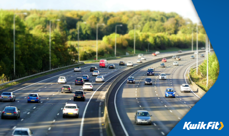 Busy UK motorway with greenery in the background.