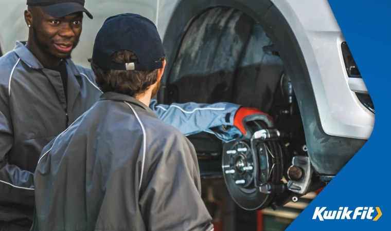 Technicians in discussion whilst changing a wheel.