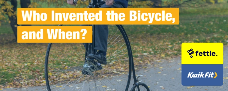 A person riding a penny farthing along a park path in autumn.