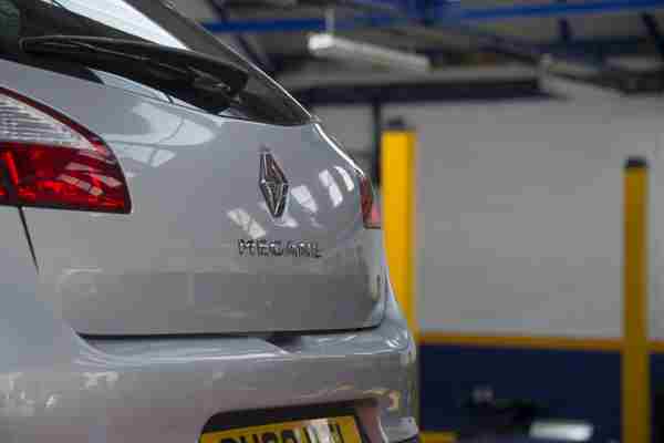 A silver car in a garage having its structure and body shell checked during an MOT